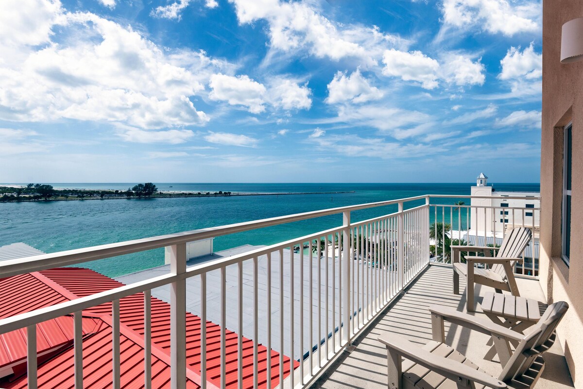 A balcony with a view of the ocean and a distant island.