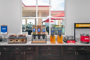A breakfast bar with a bakery section, a coffee station with various drink dispensers, and a toaster. - Hampton Inn & Suites Clearwater Beach (Clearwater Beach)