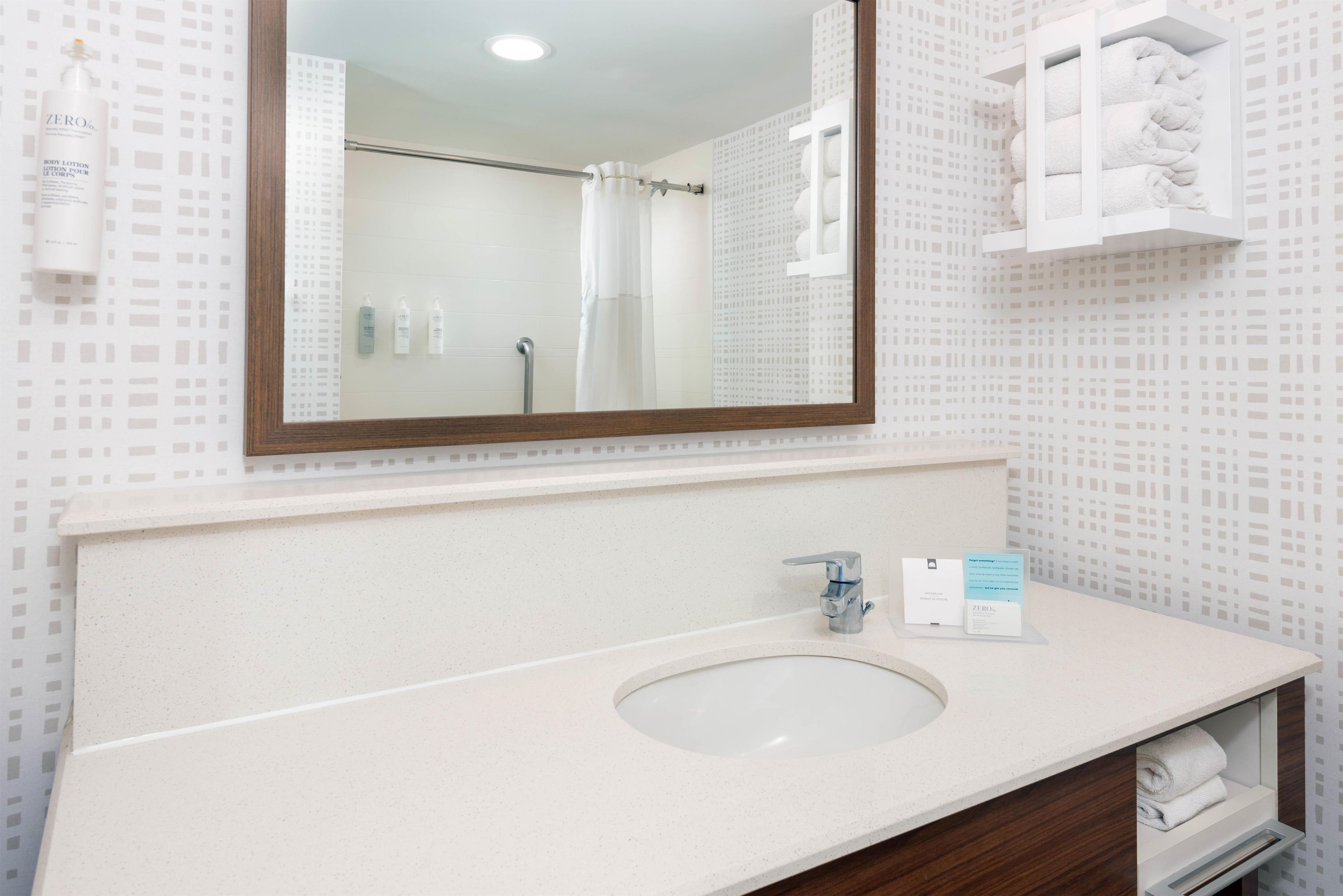 A bathroom with a sink, mirror, and towel rack.