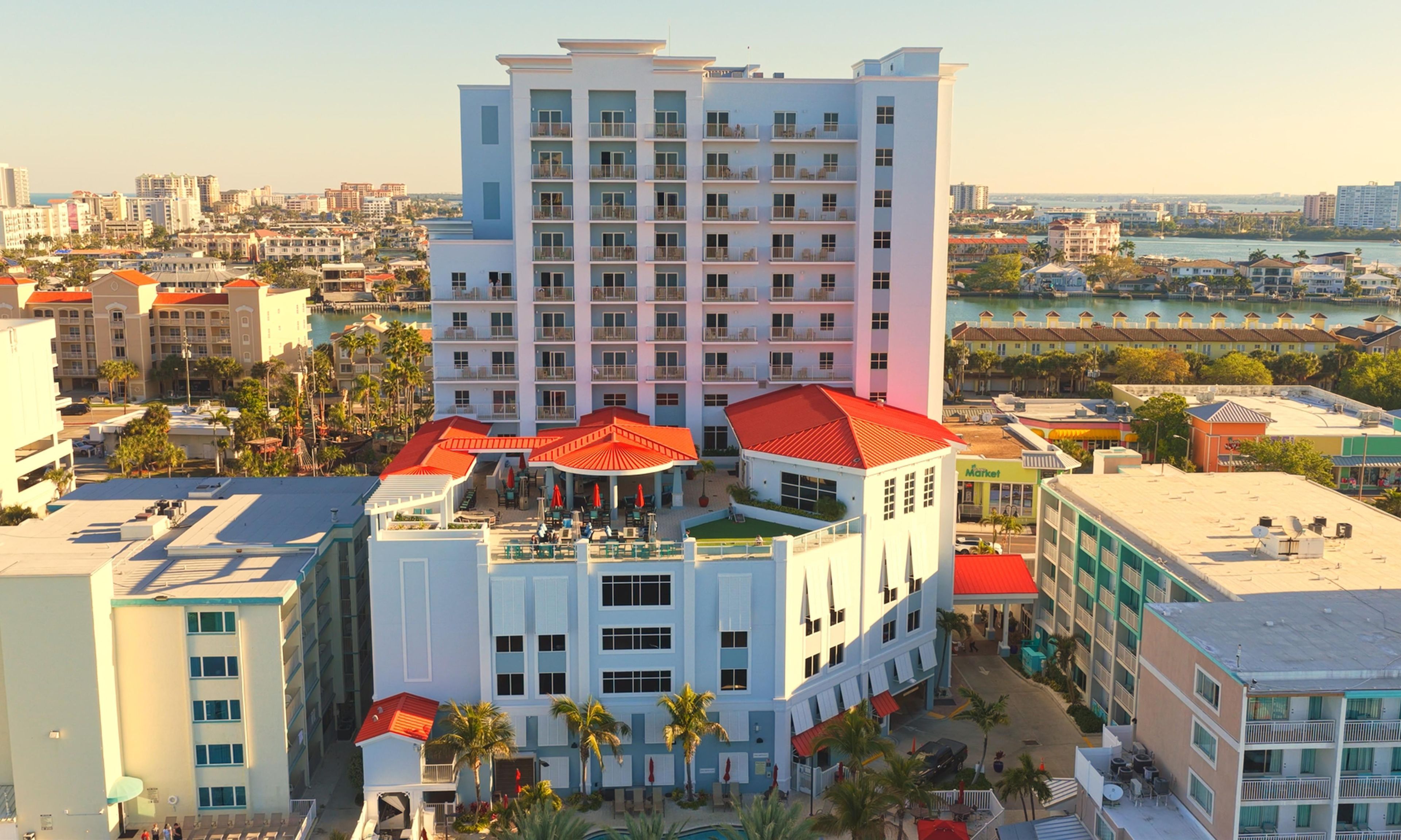 A multi-story hotel with a pool area, outdoor seating, and a view of the surrounding cityscape.