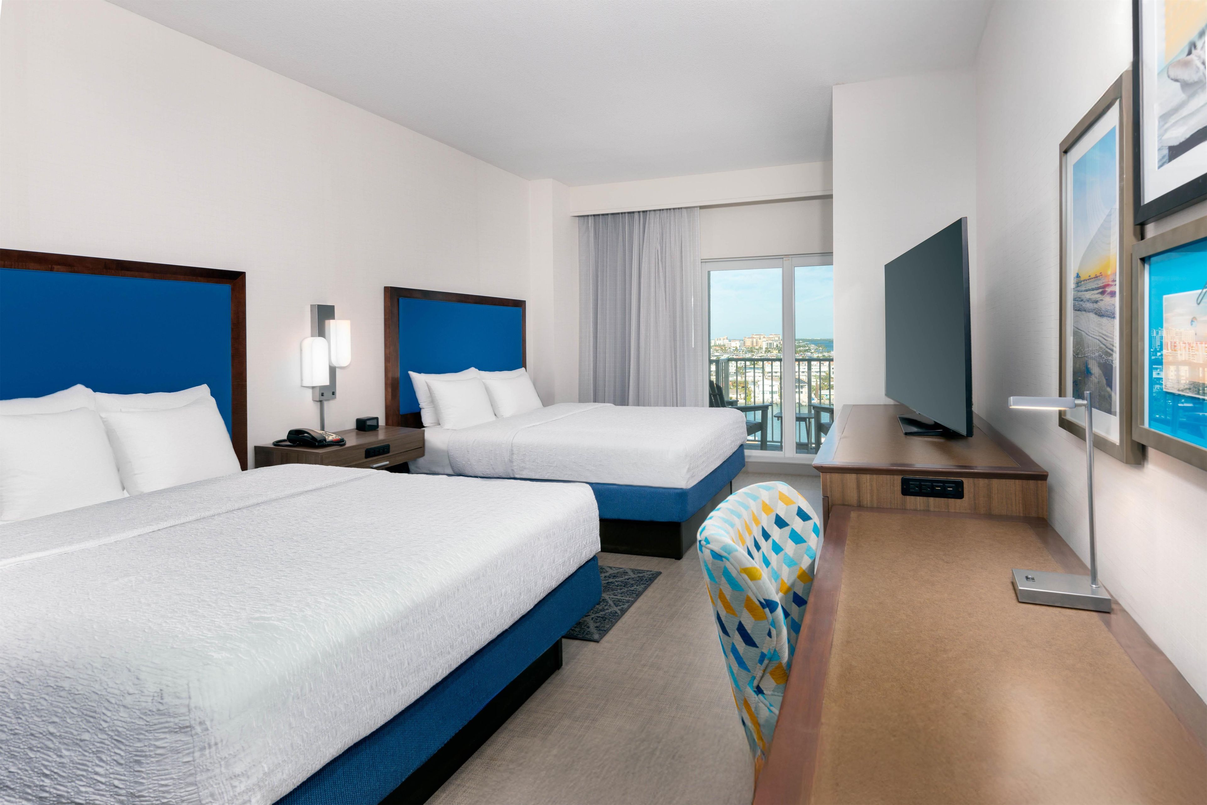 Une chambre d’hôtel avec deux lits, un bureau, une télévision et une vue sur la ville.