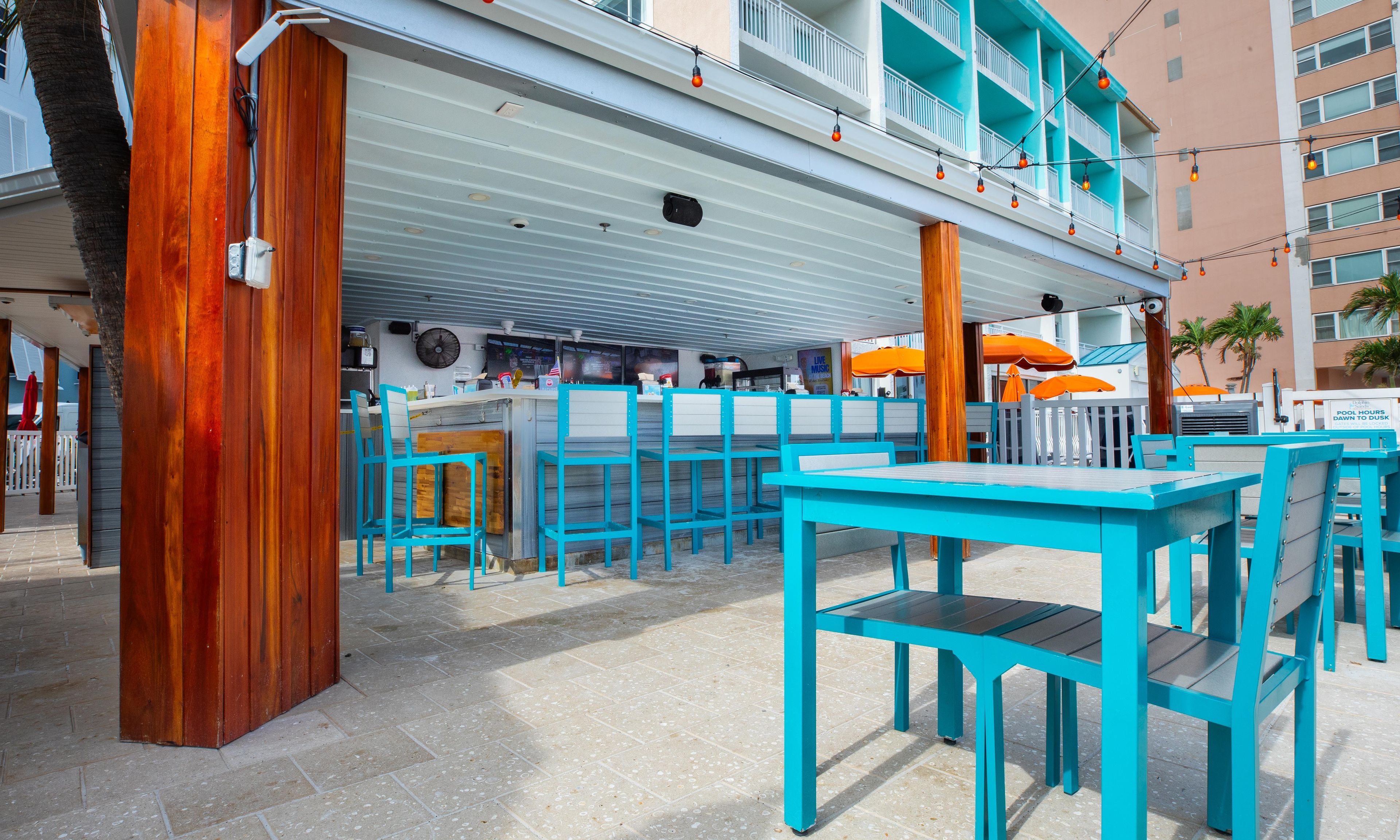 Zona de bar al aire libre con mobiliario turquesa y vistas a la piscina.