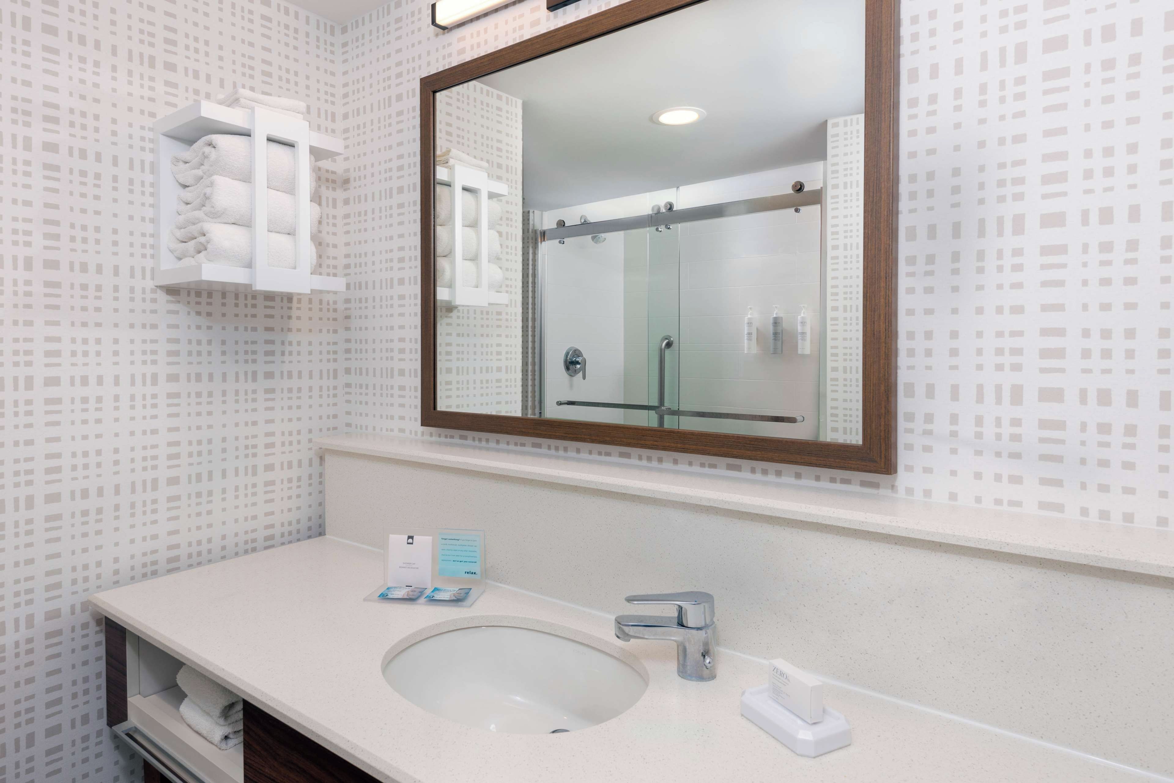 Un baño con un espejo grande, un lavabo y un perchero para toallas.