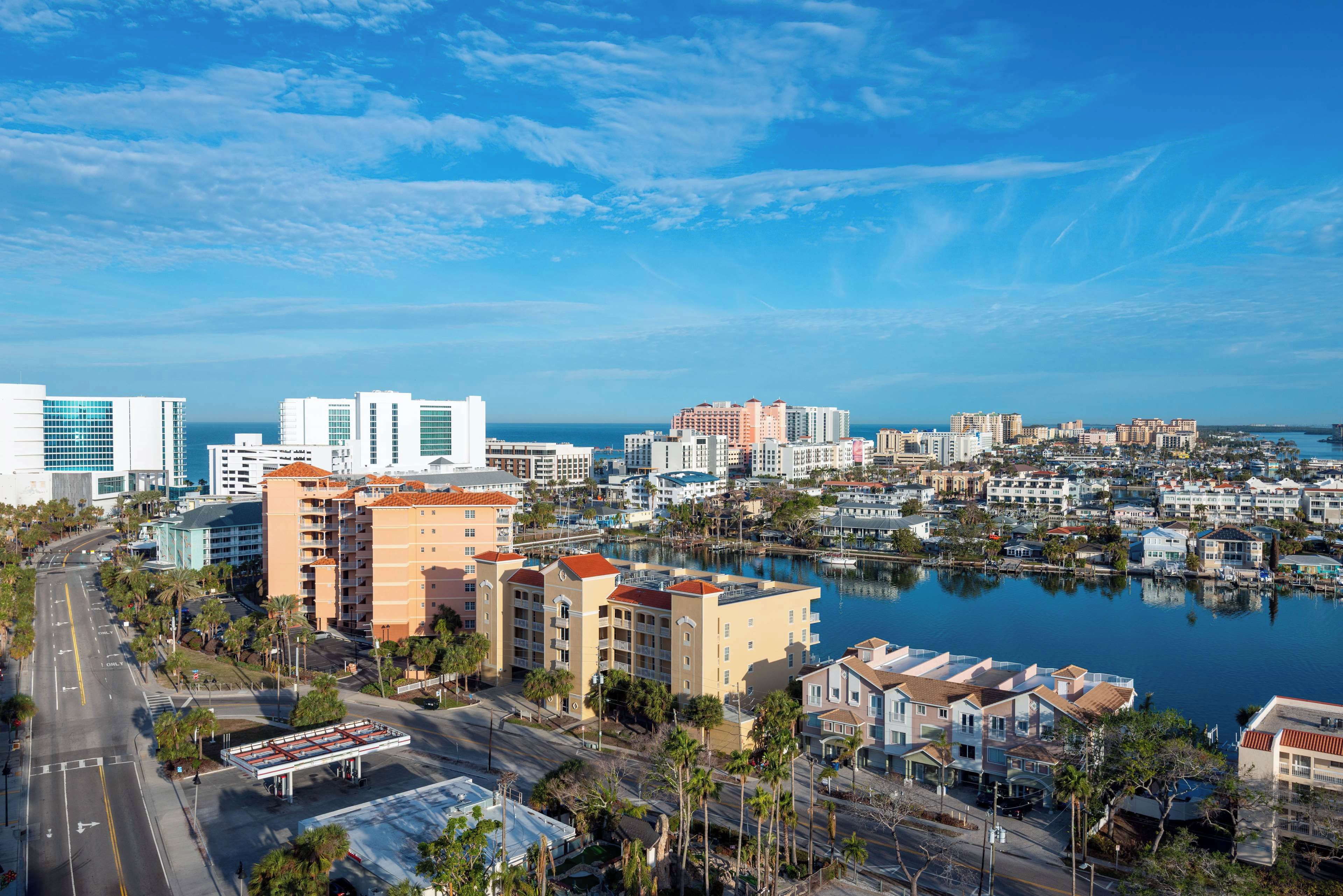 A coastal cityscape with a marina, high-rise buildings, and a clear sky.