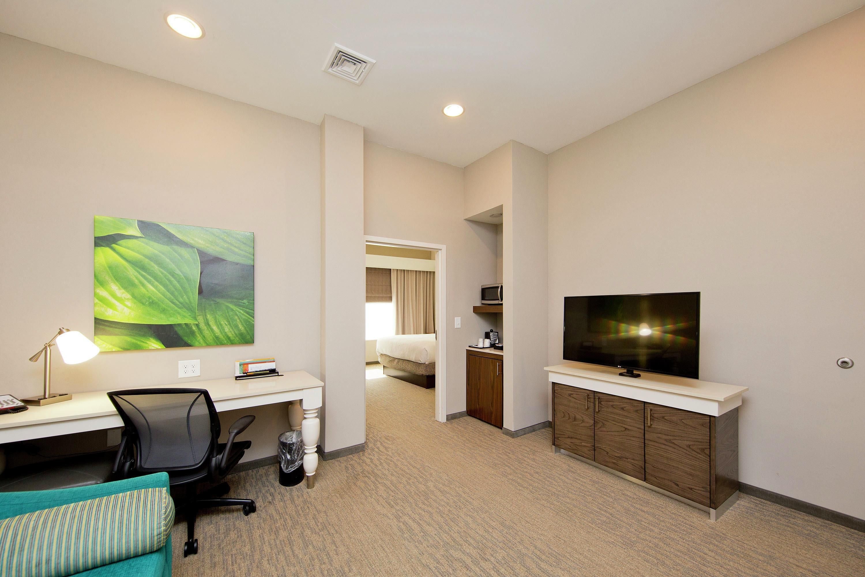 A hotel room with a desk, chair, television, and a bed.