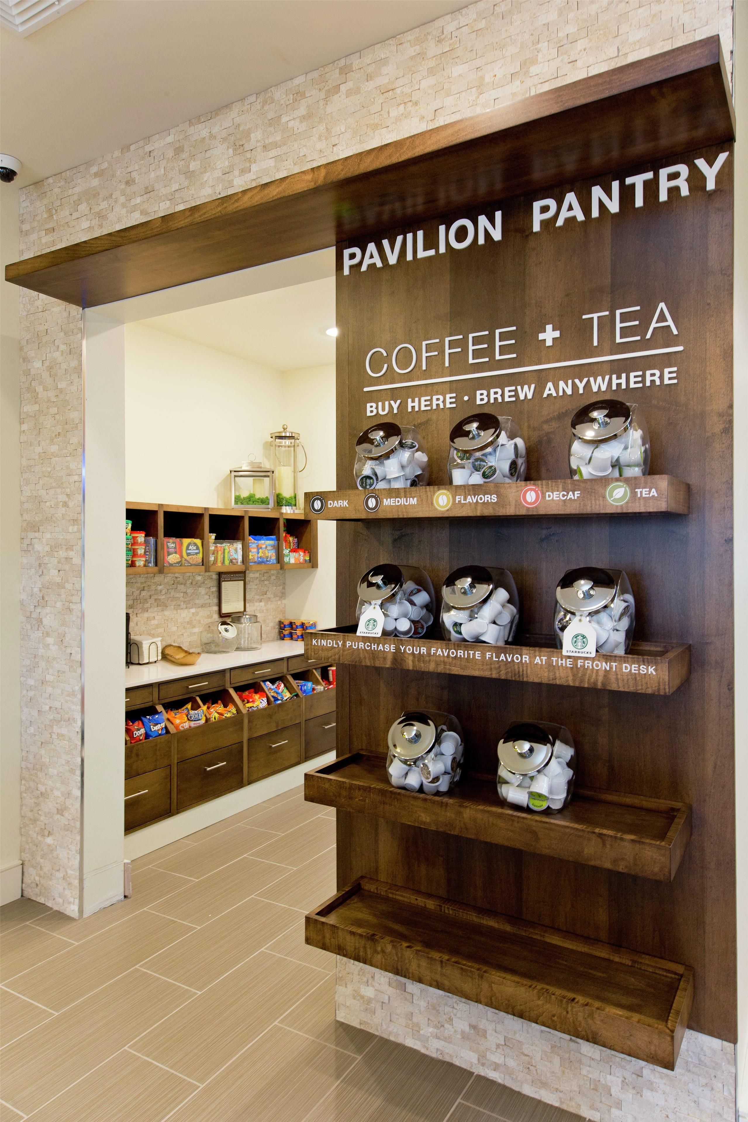 Una estación de café y té con dispensadores etiquetados para distintos tipos de café y té.