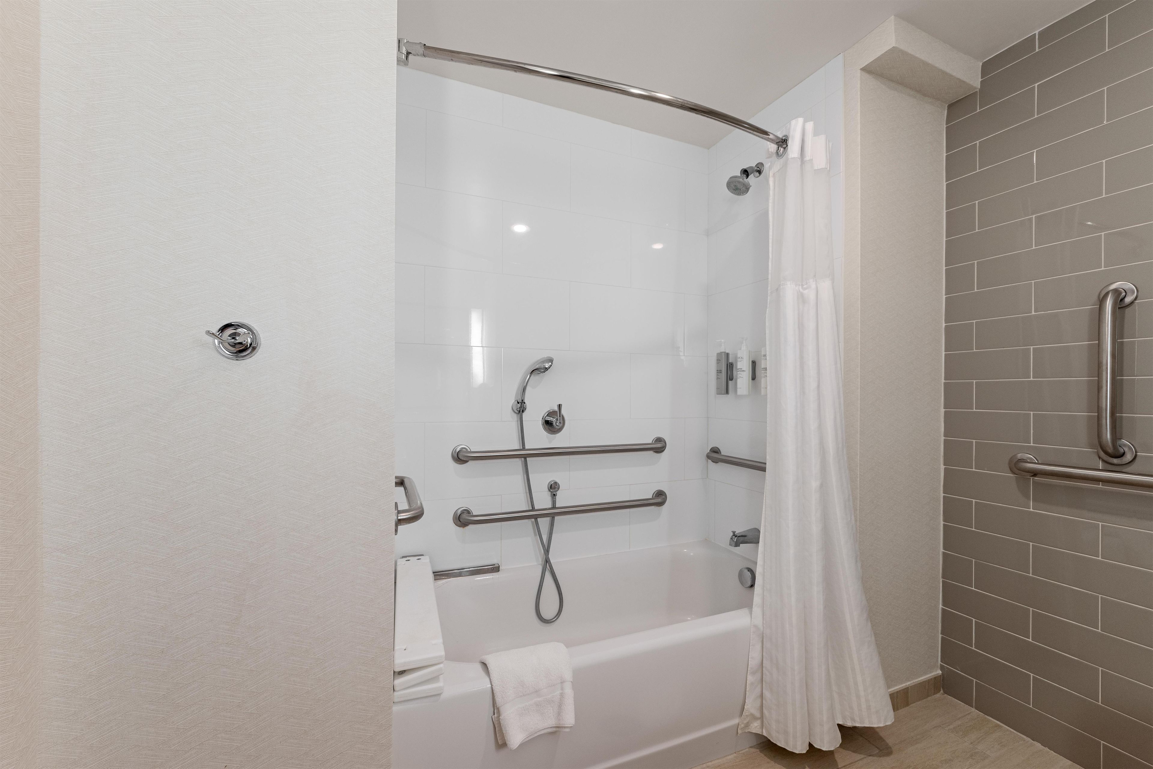 A modern bathroom with a walk-in shower, grab bars, and a bathtub.