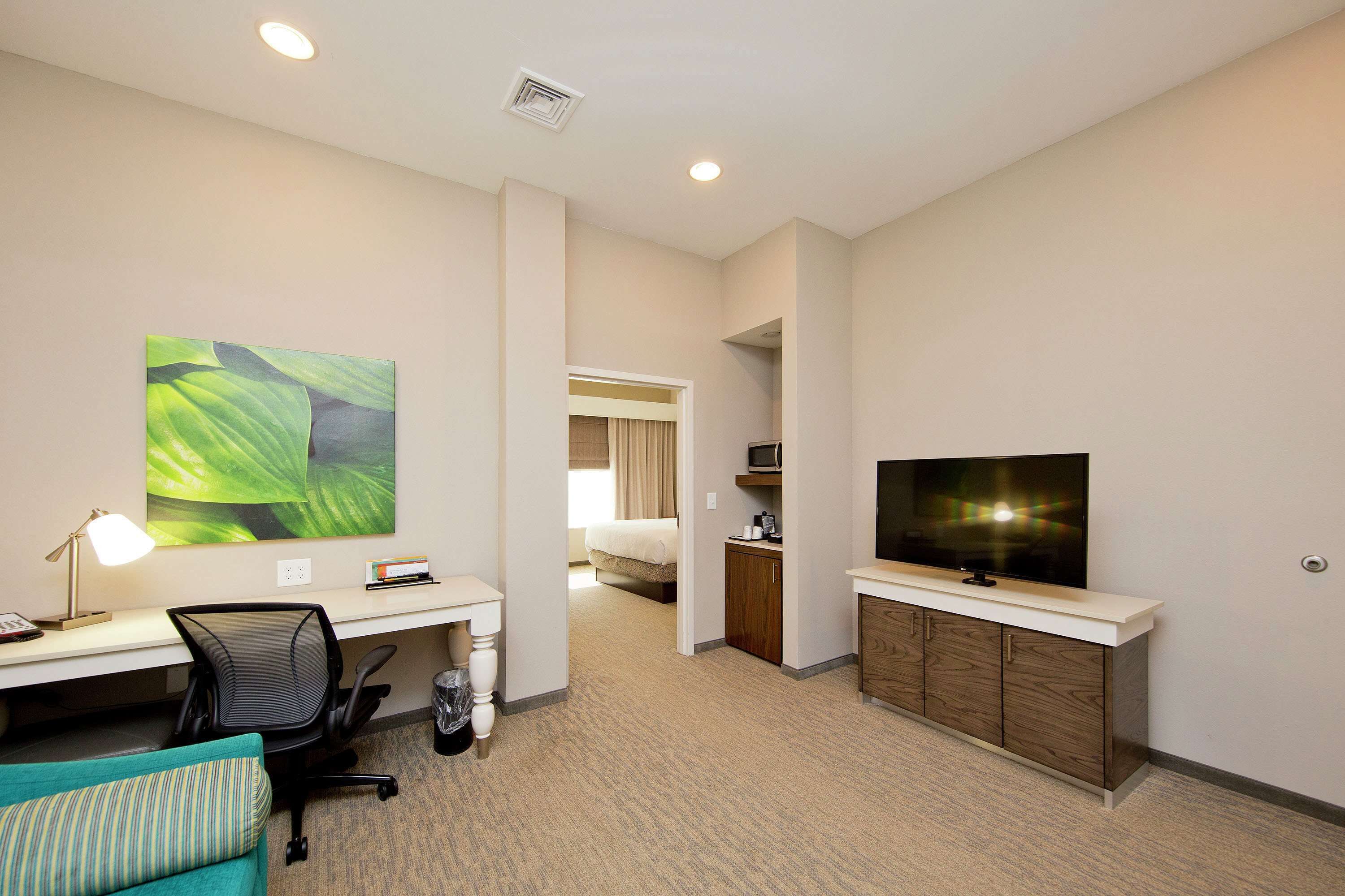 A hotel room with a desk, chair, television, and a bed.