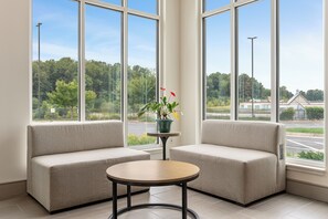 A room with two sofas facing a large window, a small round table, and a potted plant.
