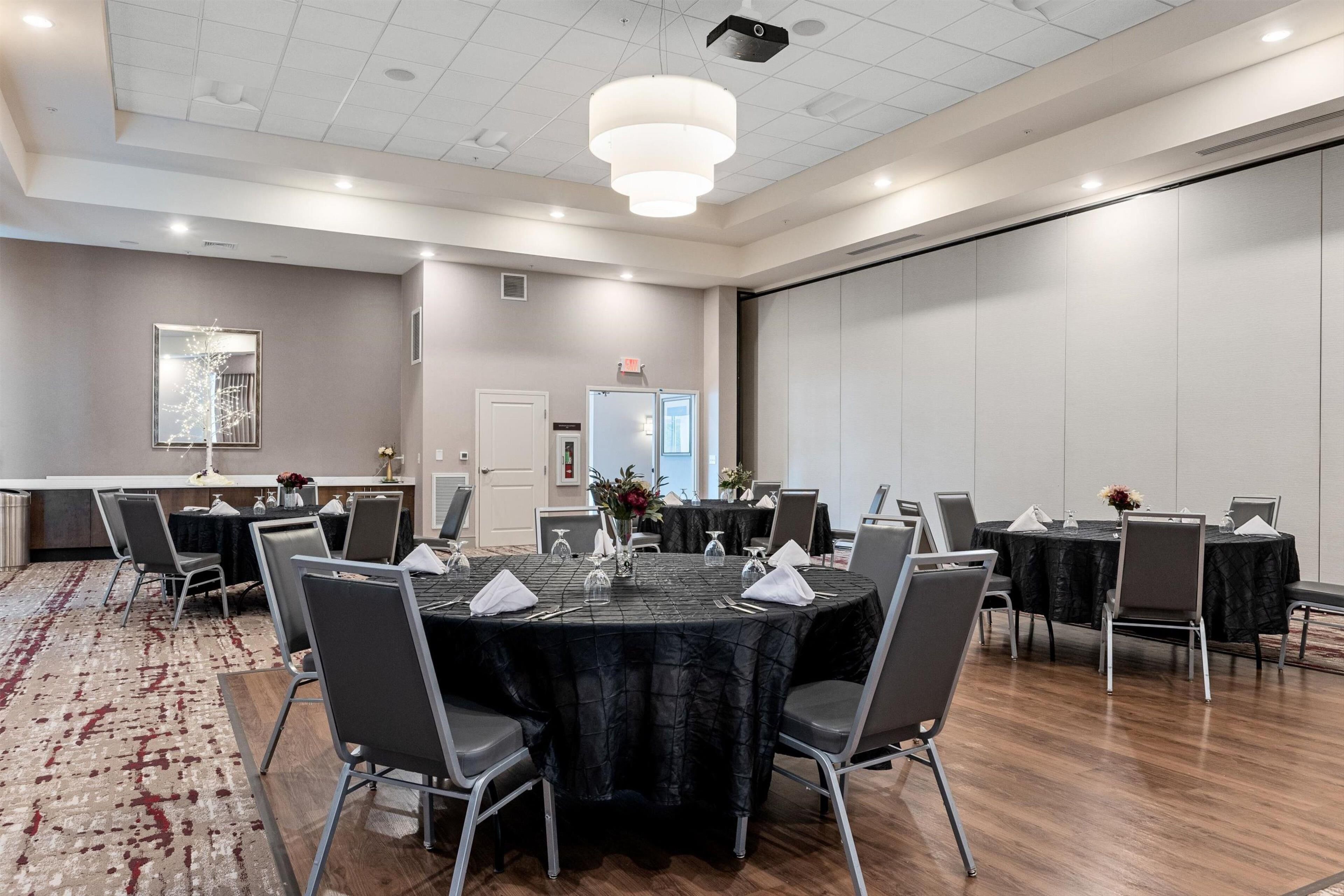 A conference room with round tables, chairs, and a projector screen.