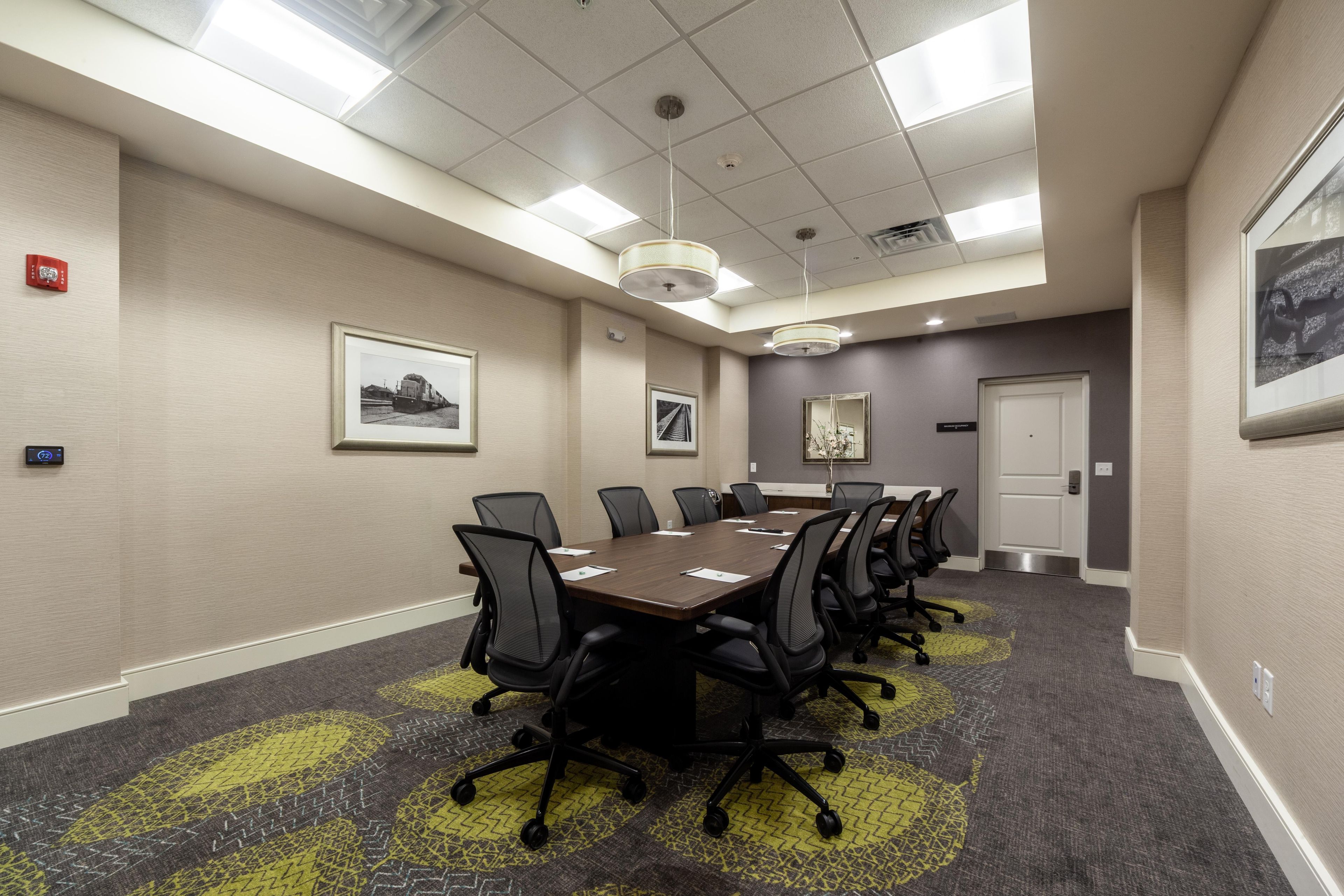 A conference room with a long table, chairs, and a carpeted floor.