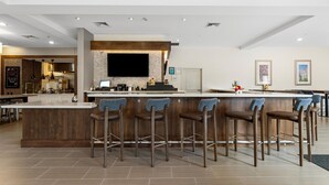 Una cocina moderna con barra, taburetes de madera y una isla grande.