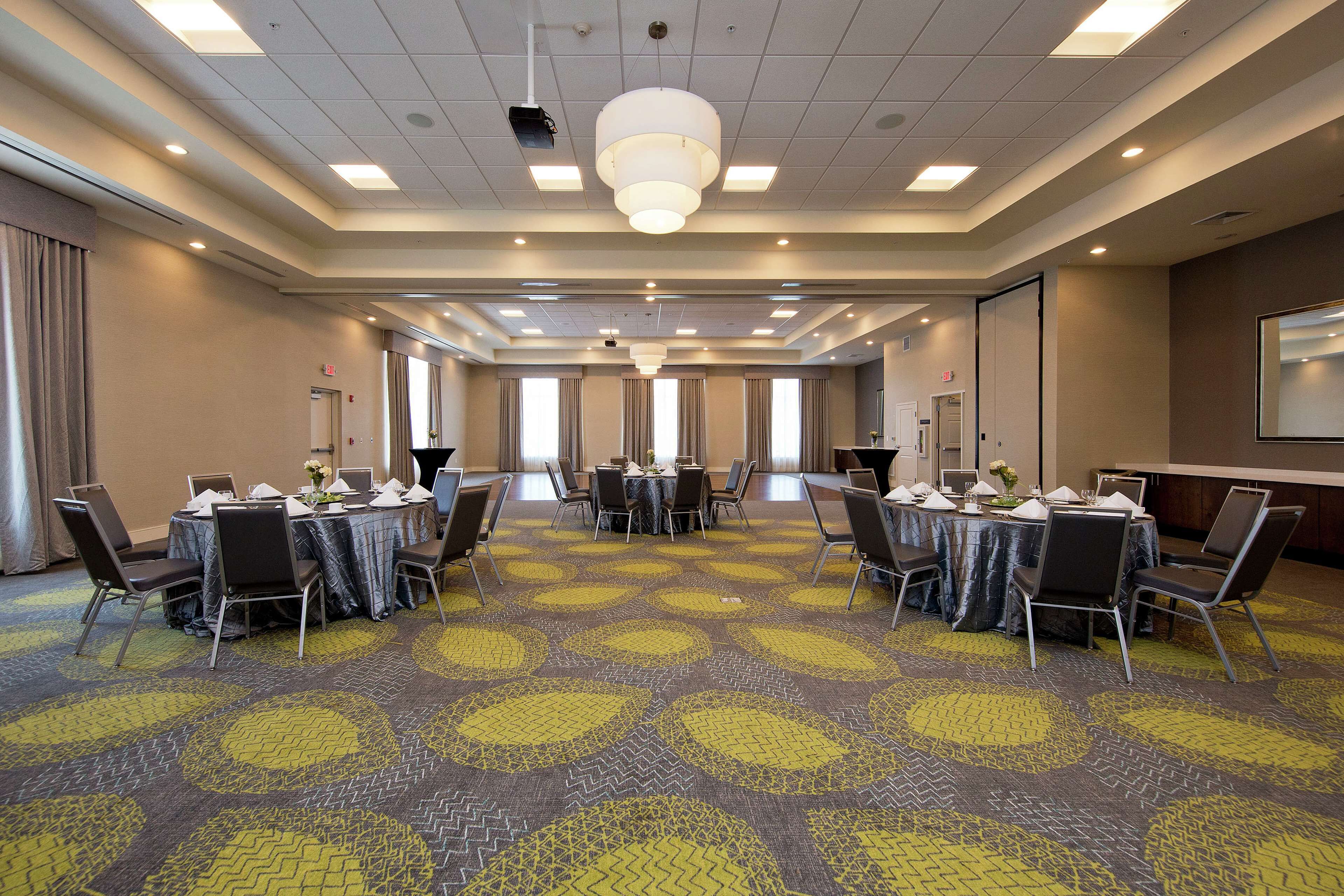 A conference room with round tables, chairs, and a carpeted floor.