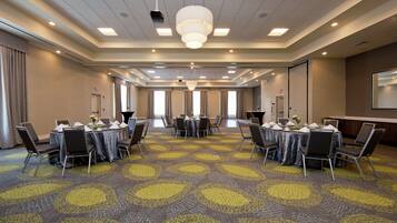 A conference room with round tables, chairs, and a carpeted floor.