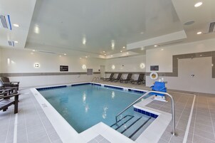 A swimming pool with a tiled deck, lounge chairs, and a lifeguard chair.