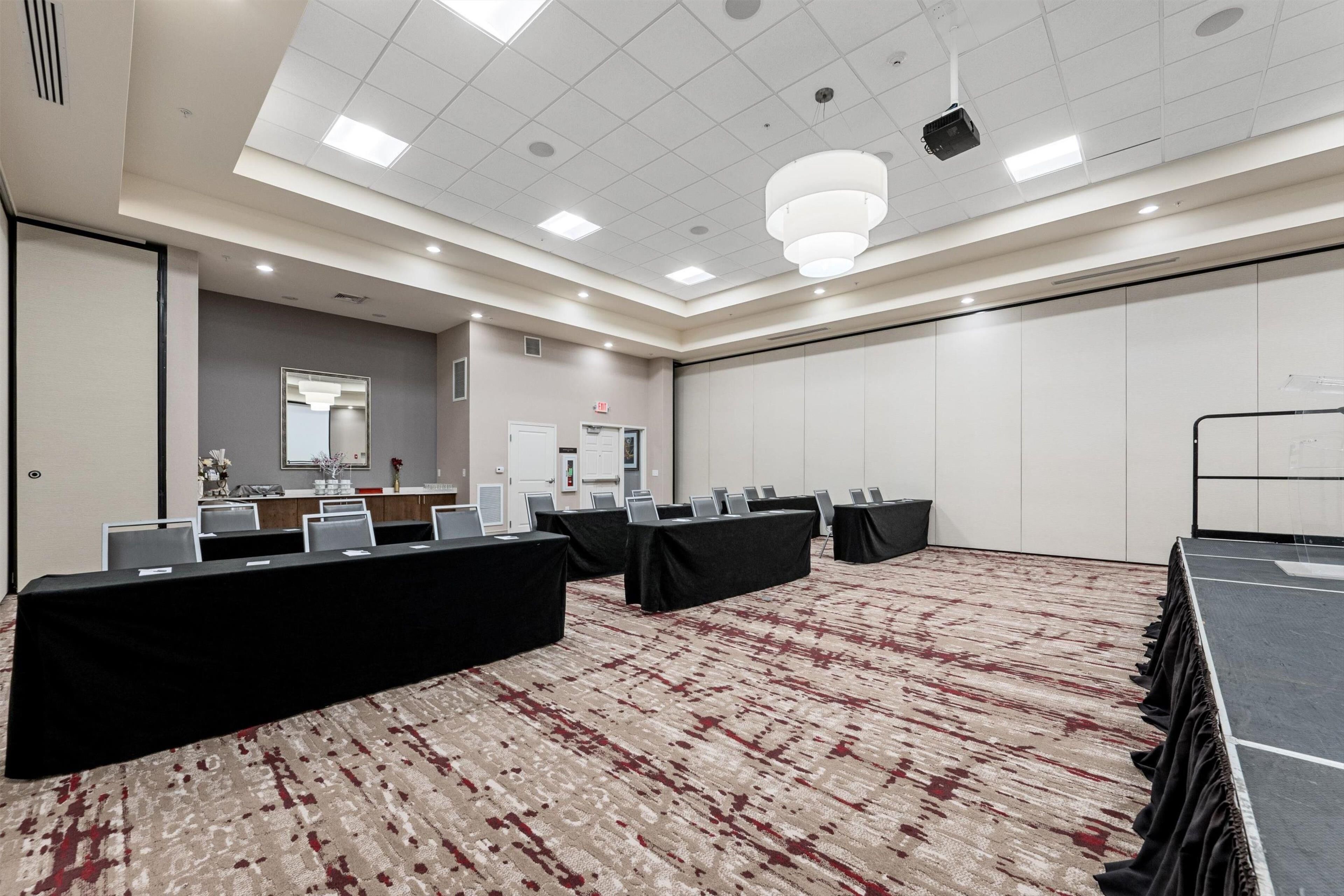 Un salón de conferencias con una larga mesa, sillas y piso alfombrado.