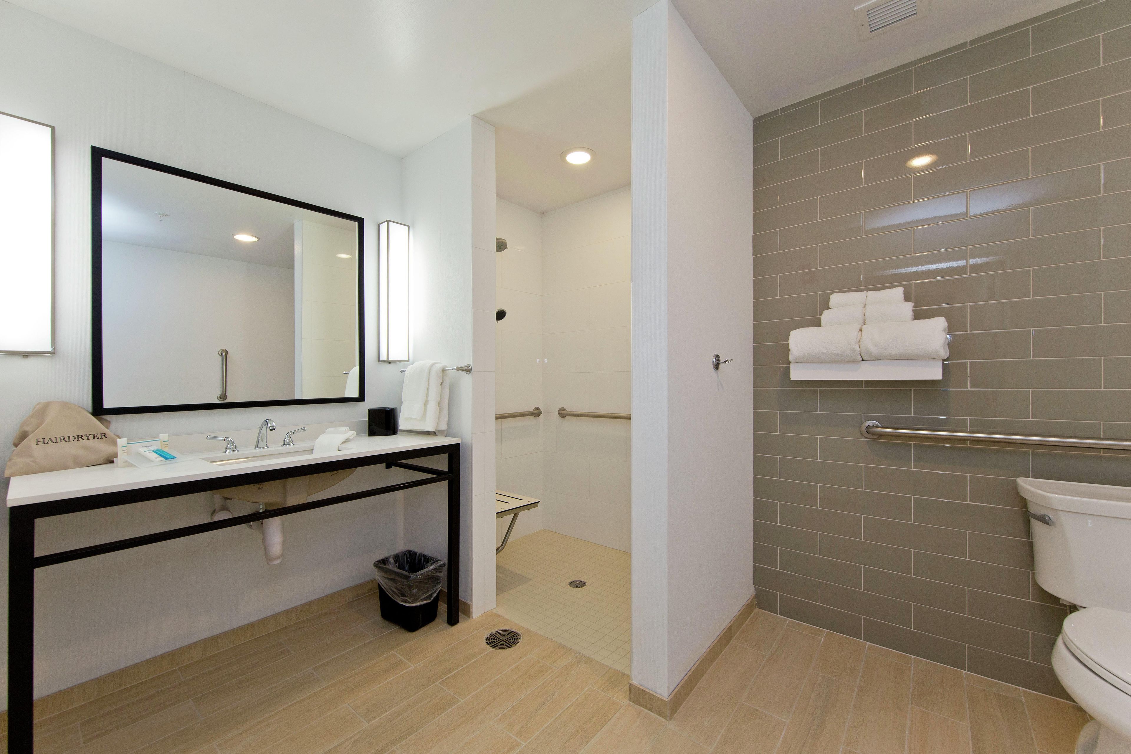 A modern bathroom with a sink, mirror, towel rack, and a shower area.