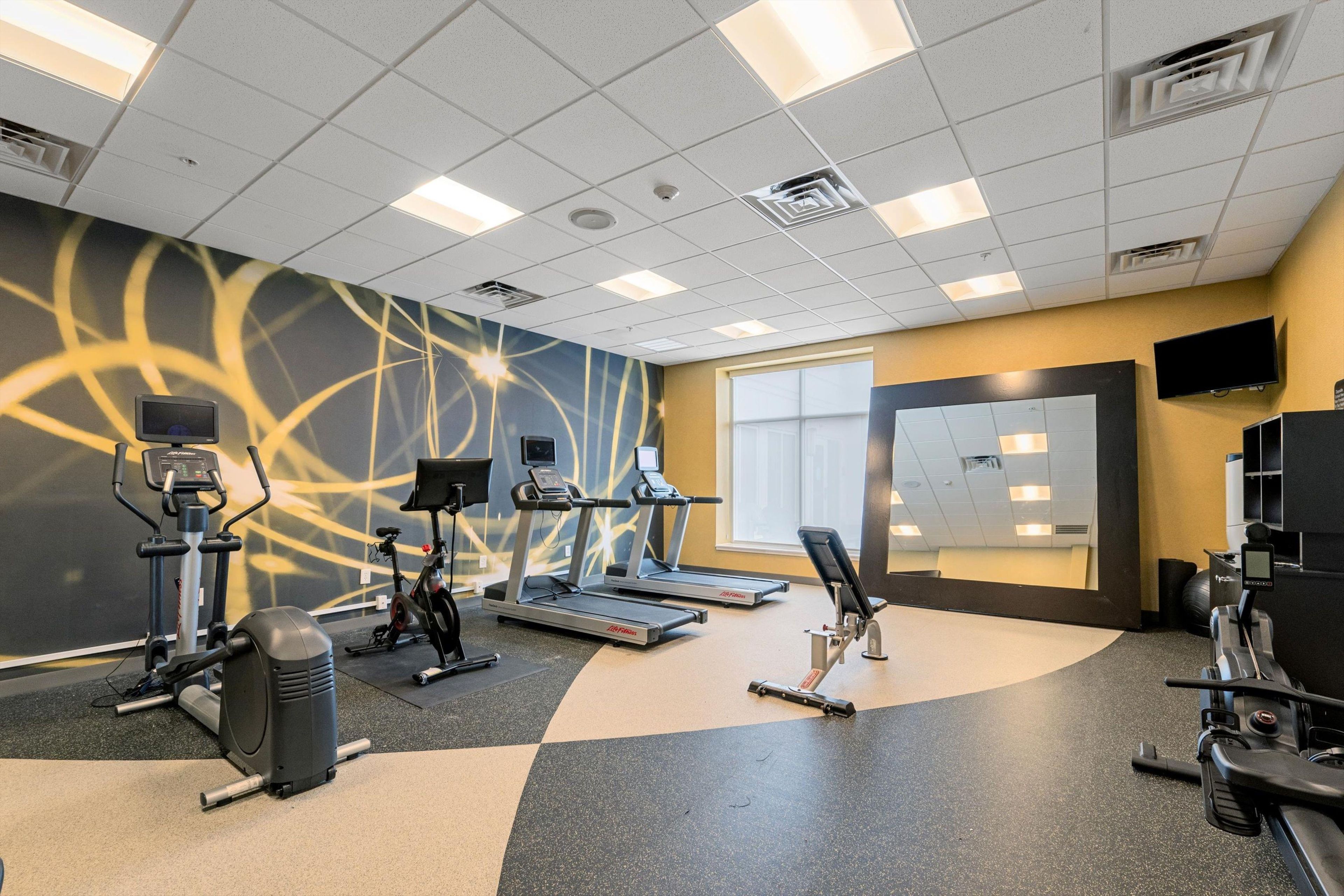 A gym with treadmills, elliptical machines, and a stationary bike.