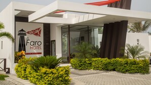 Una entrada de hotel moderna con un letrero llamativo, puertas de cristal y jardines bien cuidados.