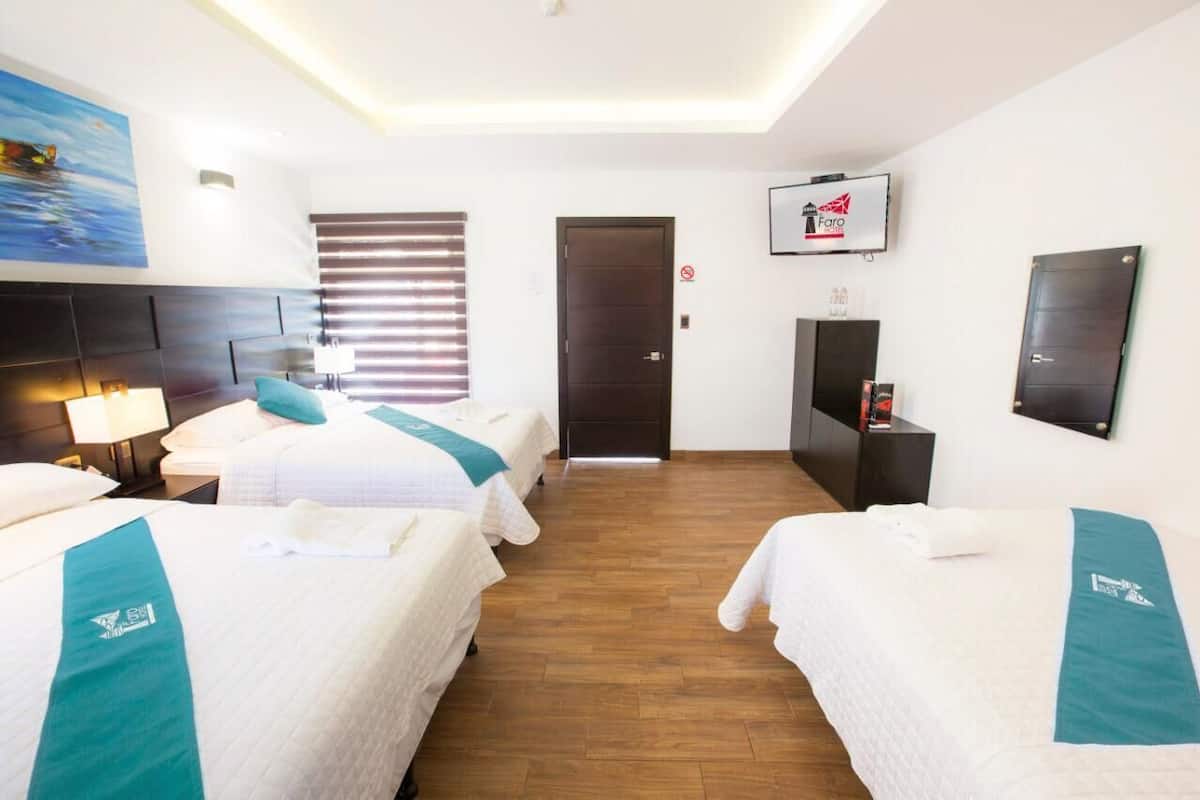 Habitación de hotel con dos camas, televisión, escritorio y puerta.
