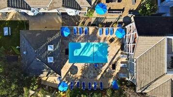 An aerial view of a residential area with a swimming pool surrounded by lounge chairs and umbrellas, indicating a private outdoor space.