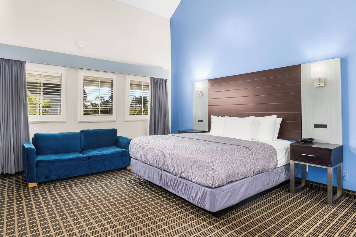 A hotel room with a large bed, a blue sofa, and a patterned carpet.