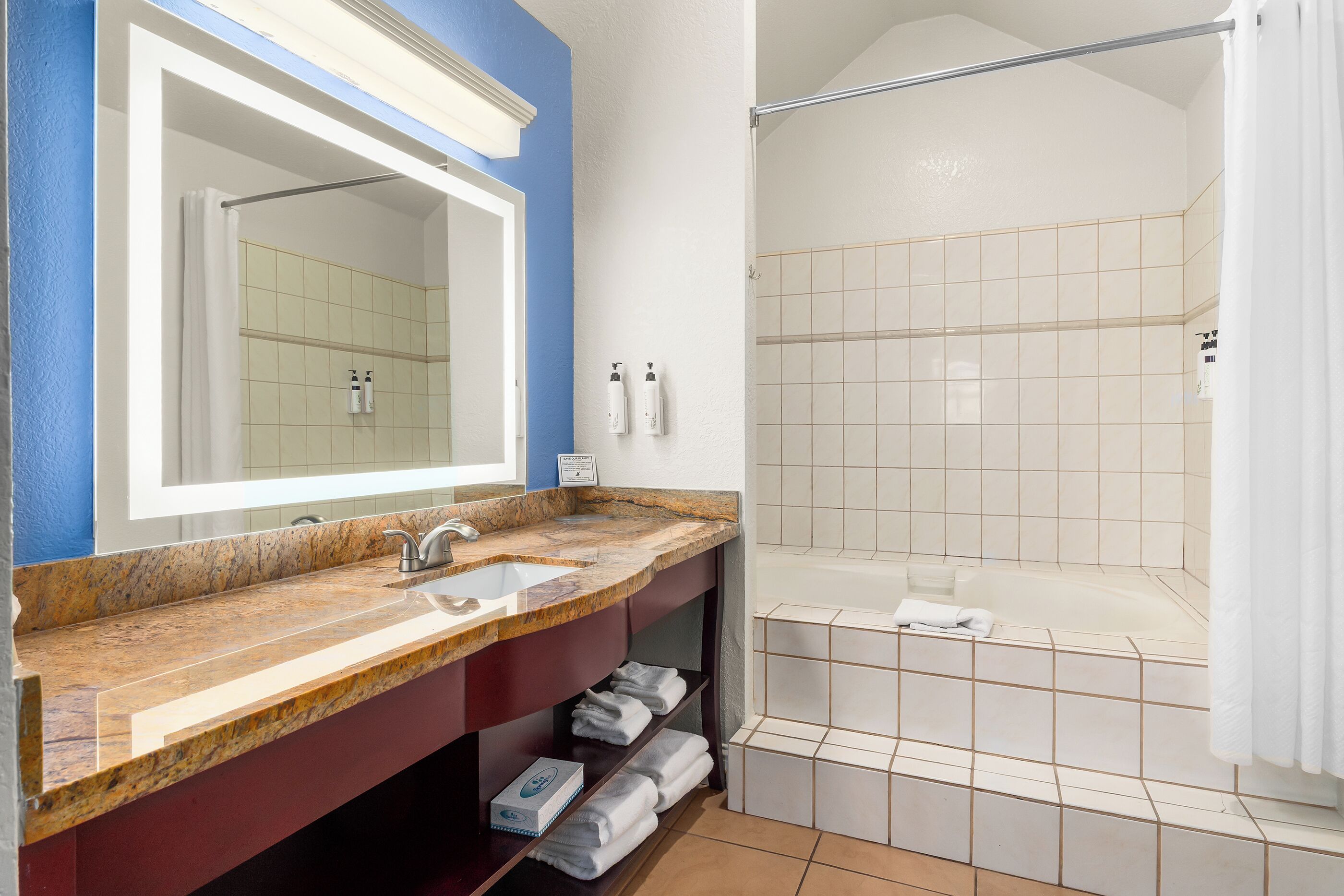 A bathroom with a marble sink, a large mirror, a shower with a glass door, and a bathtub.