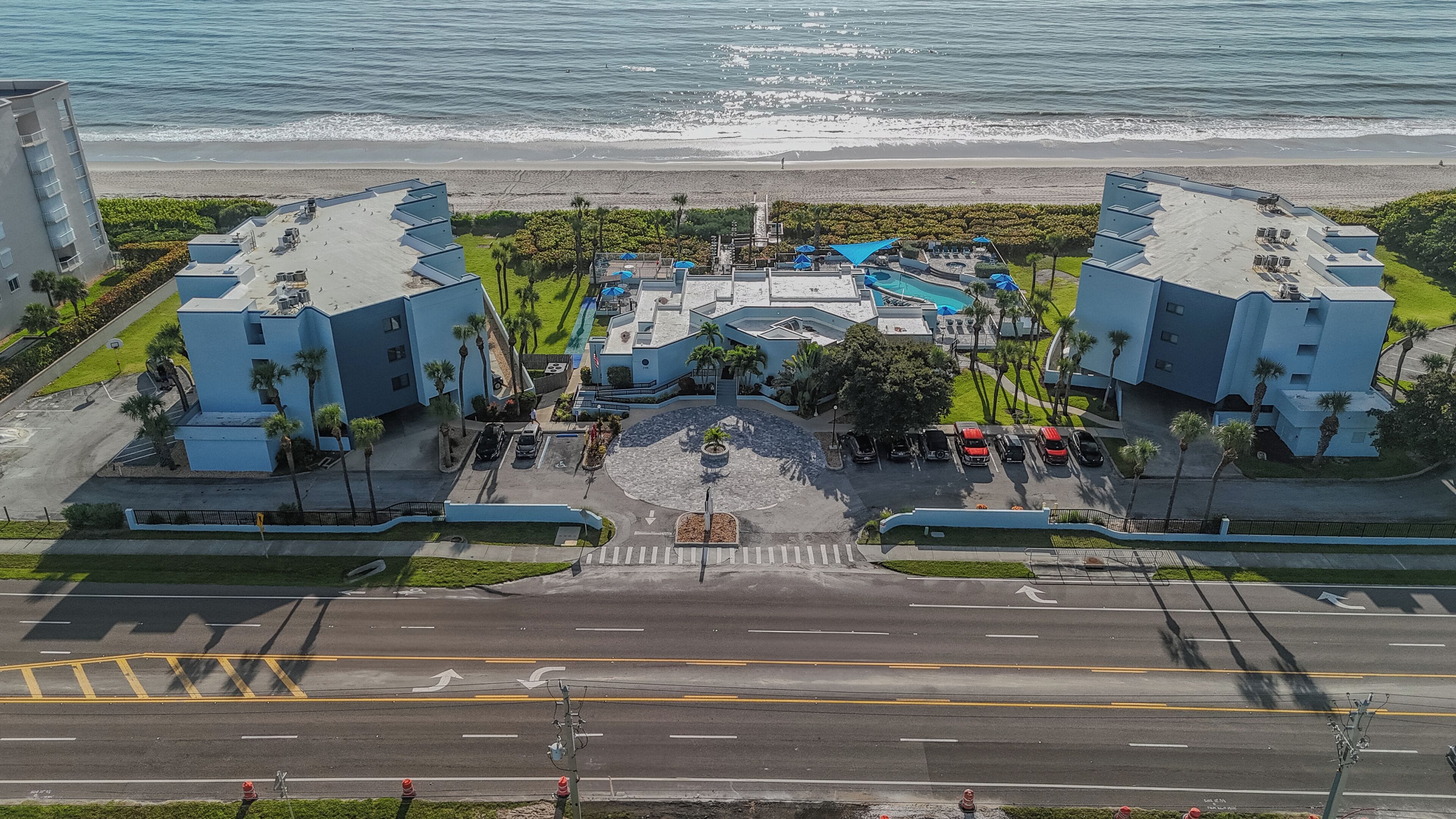 Ein Hotel mit Pool, Parkplatz und Blick auf den Strand.
