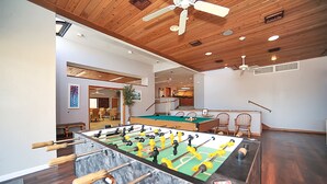 Une pièce spacieuse équipée d’un baby-foot, avec un plafond en bois et une table de billard.