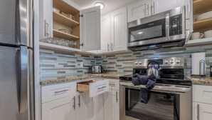 Une cuisine moderne dotée d’appareils électroménagers en acier inoxydable, de meubles blancs et d’un dosseret carrelé.