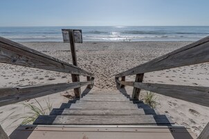 Un camino de madera que conduce a una playa arenosa, con una vista despejada del océano.