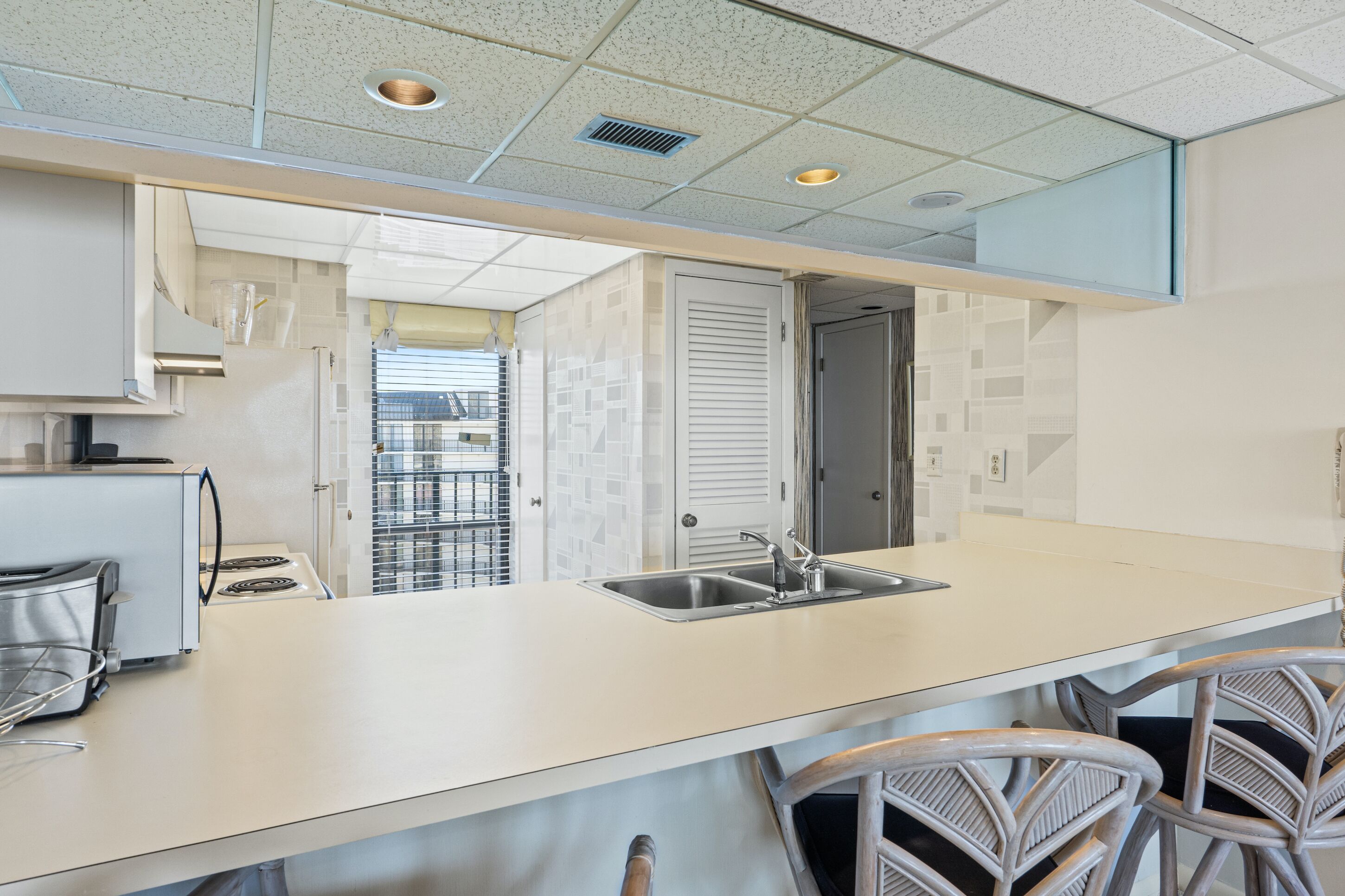 A modern kitchen with a large island, stainless steel appliances, and a view of the balcony.