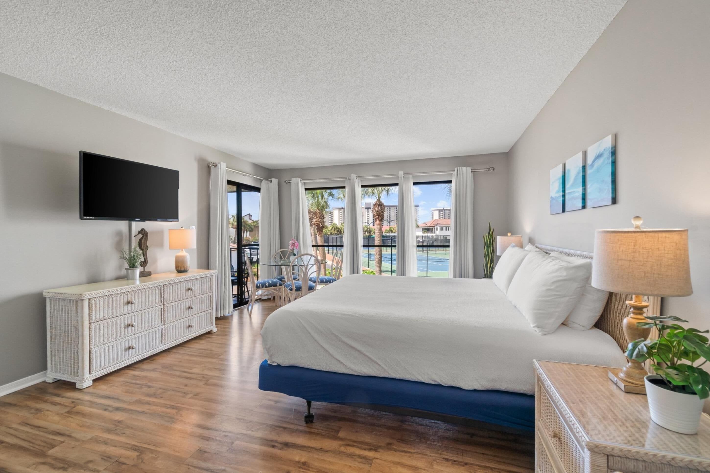 Quarto com uma cama grande, televisão, cômoda e vista para o exterior.