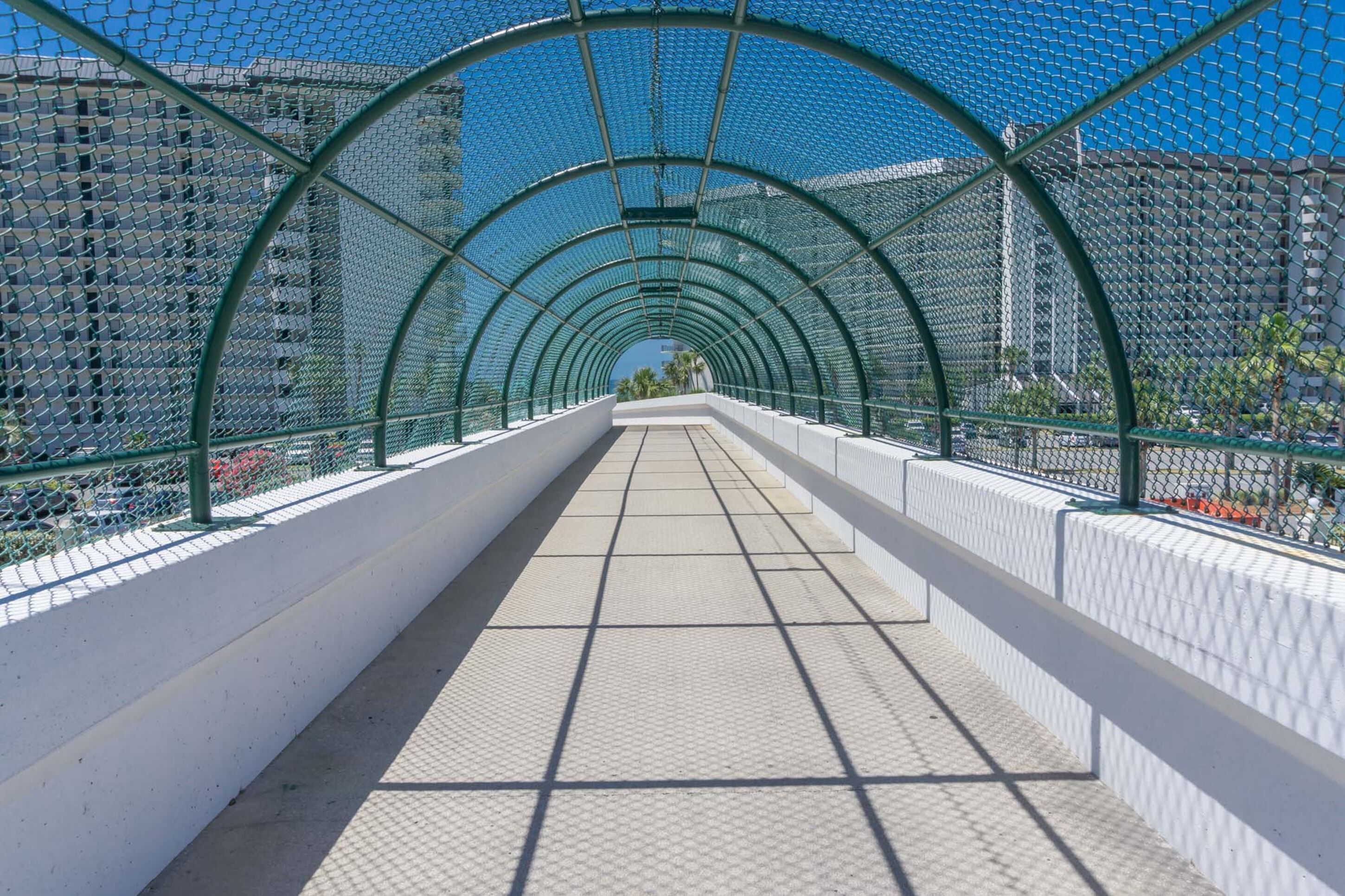 Ein überdachter Fußweg mit einem gitterförmigen Boden und Metallgeländern.