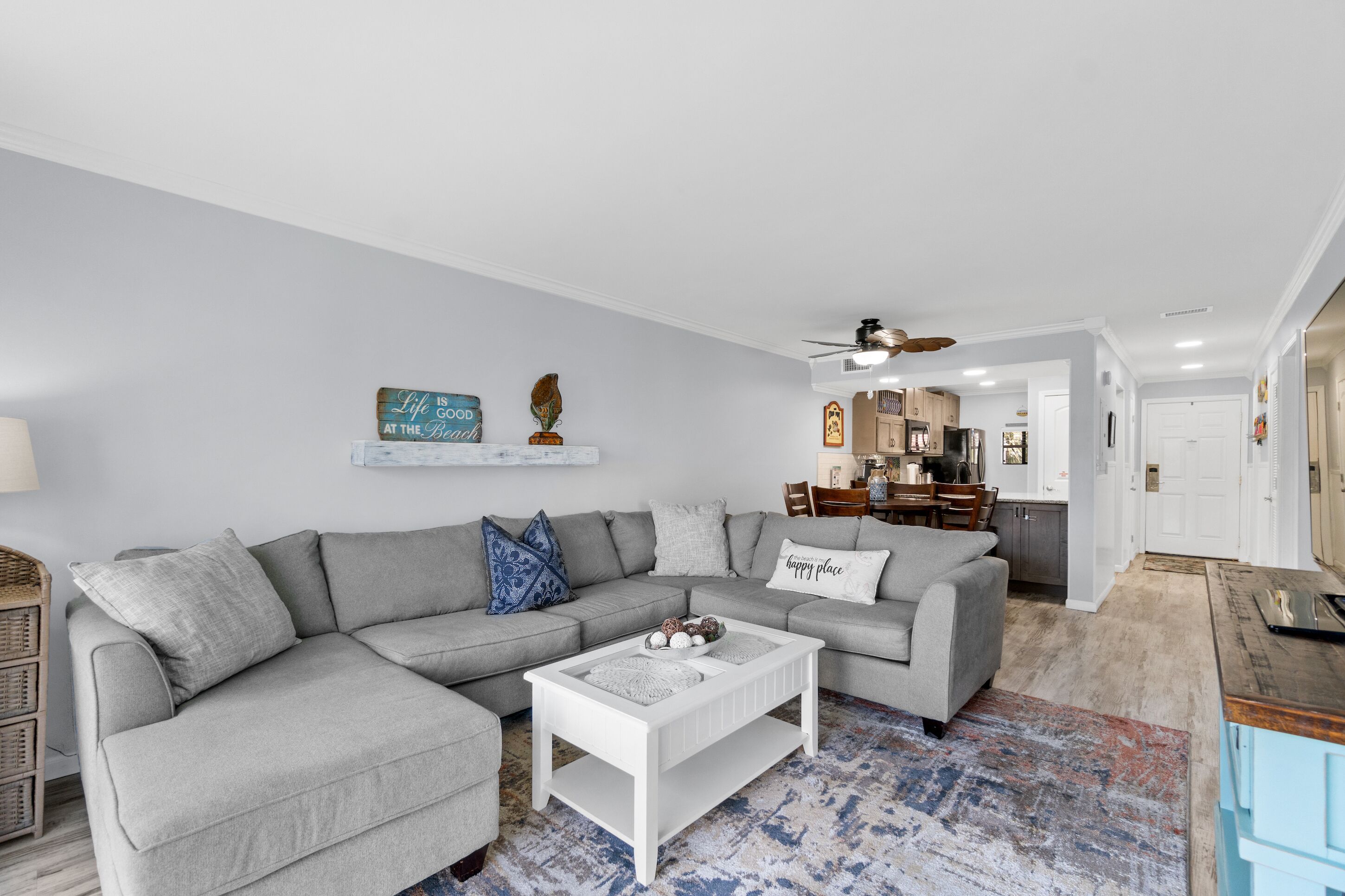 A modern living room with a grey sectional sofa, a white coffee table, and a patterned rug.