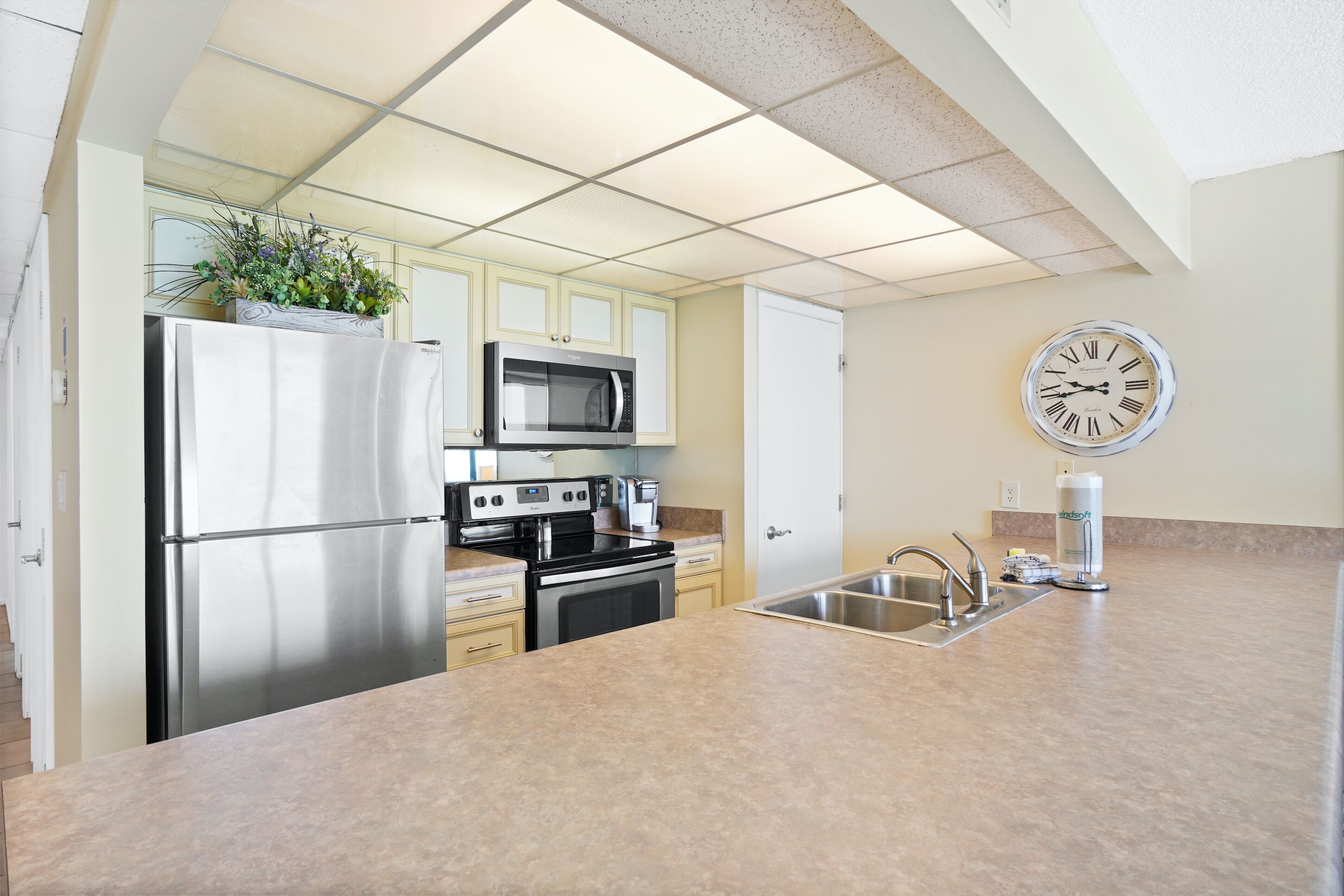 A modern kitchen with stainless steel appliances, a microwave, and a clock on the wall.