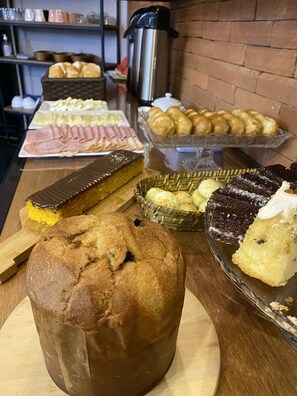Una mesa de bufé con diversas opciones de repostería, incluyendo pan, pasteles y un pastel de chocolate.