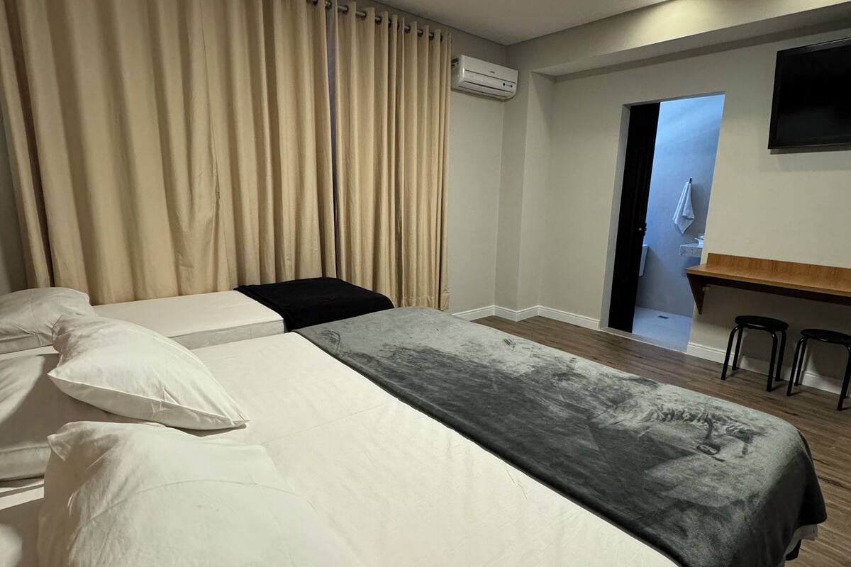 Een hotelkamer met een groot bed, een bureau en een airconditioning.