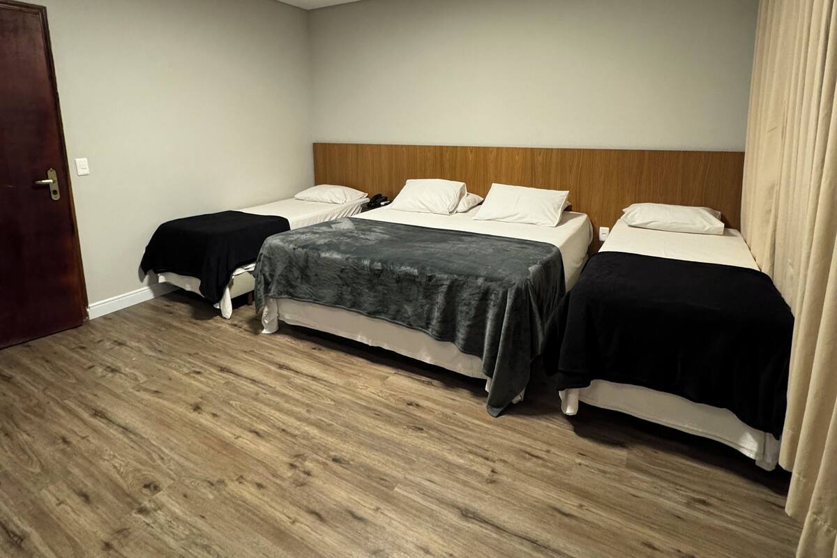 Een hotelkamer met twee bedden, een houten vloer, een plafondlamp en een deur.