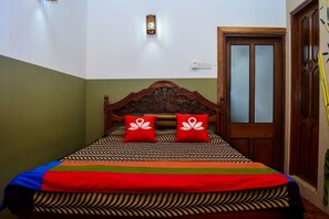 A bed with a patterned bedspread, two red pillows, and a wooden headboard. - ZEN Rooms Sellamuttu Avenue Colombo 3 (Colombo)