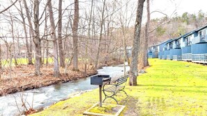 Un banco junto a un río, con un edificio al fondo.