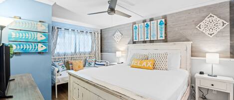 A bedroom with a bed, a nightstand, a ceiling fan, and wall art.