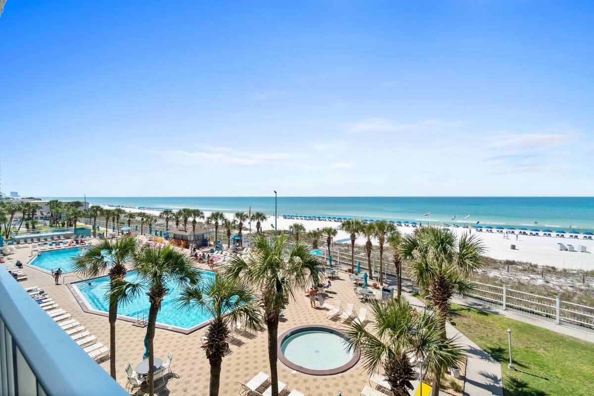 A resort with a pool area, palm trees, and a beach view.