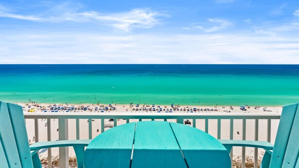 A beach view from a balcony with a wooden table, a railing, and a clear blue sky. - Summit Beach Resort by Panhandle Getaways (Panama City Beach)