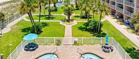 A hotel pool area with two pools, palm trees, and a beach view.