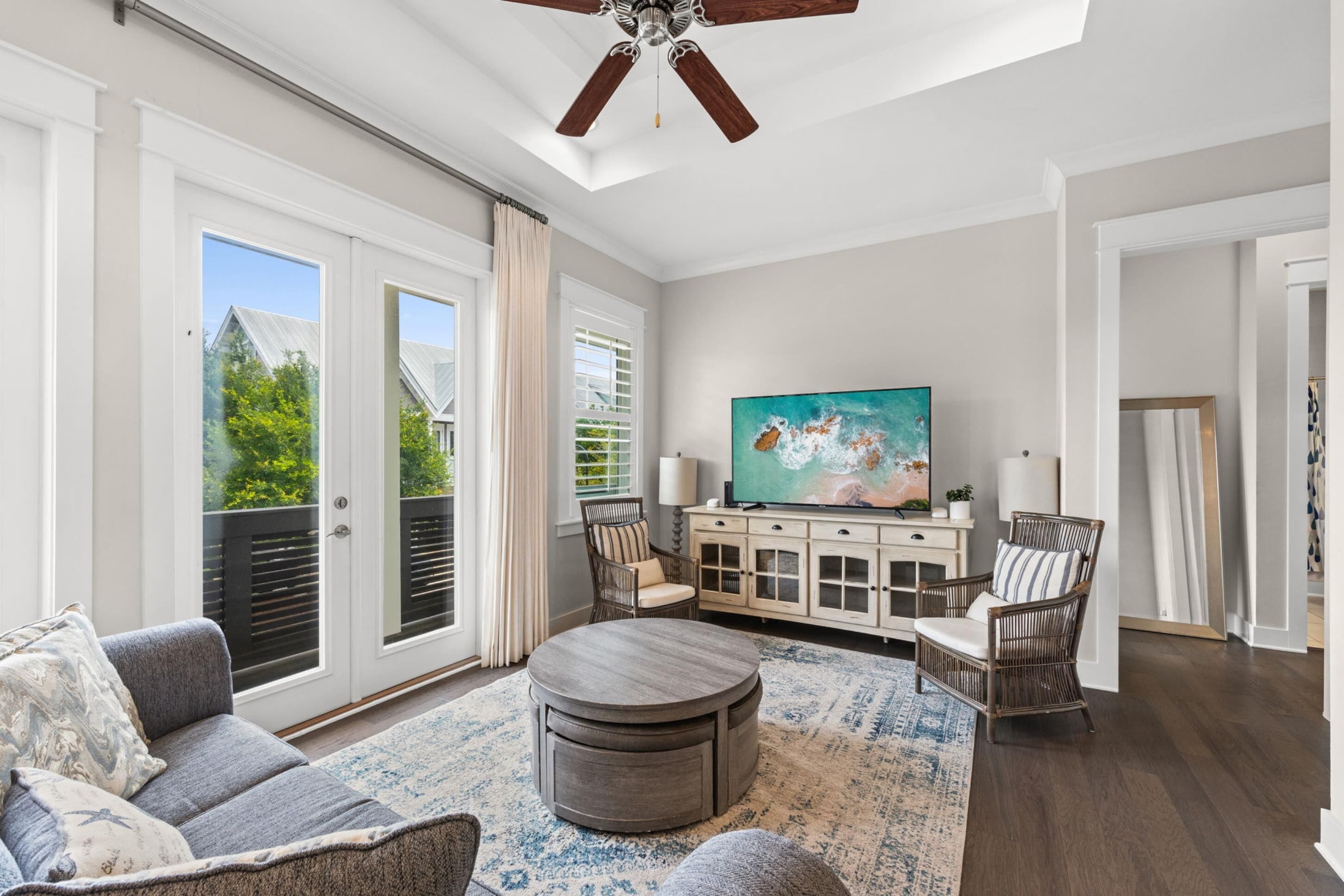 A spacious living room with a large TV, comfortable seating, and a ceiling fan.