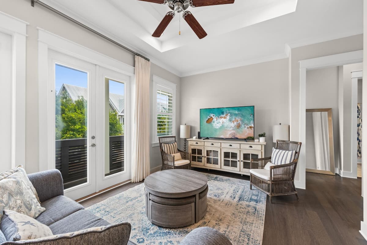 A spacious living room with a large TV, comfortable seating, and a ceiling fan.
