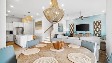 Una cocina moderna con armarios blancos, un refrigerador de acero inoxidable y un comedor con mesa de madera y sillas azules.