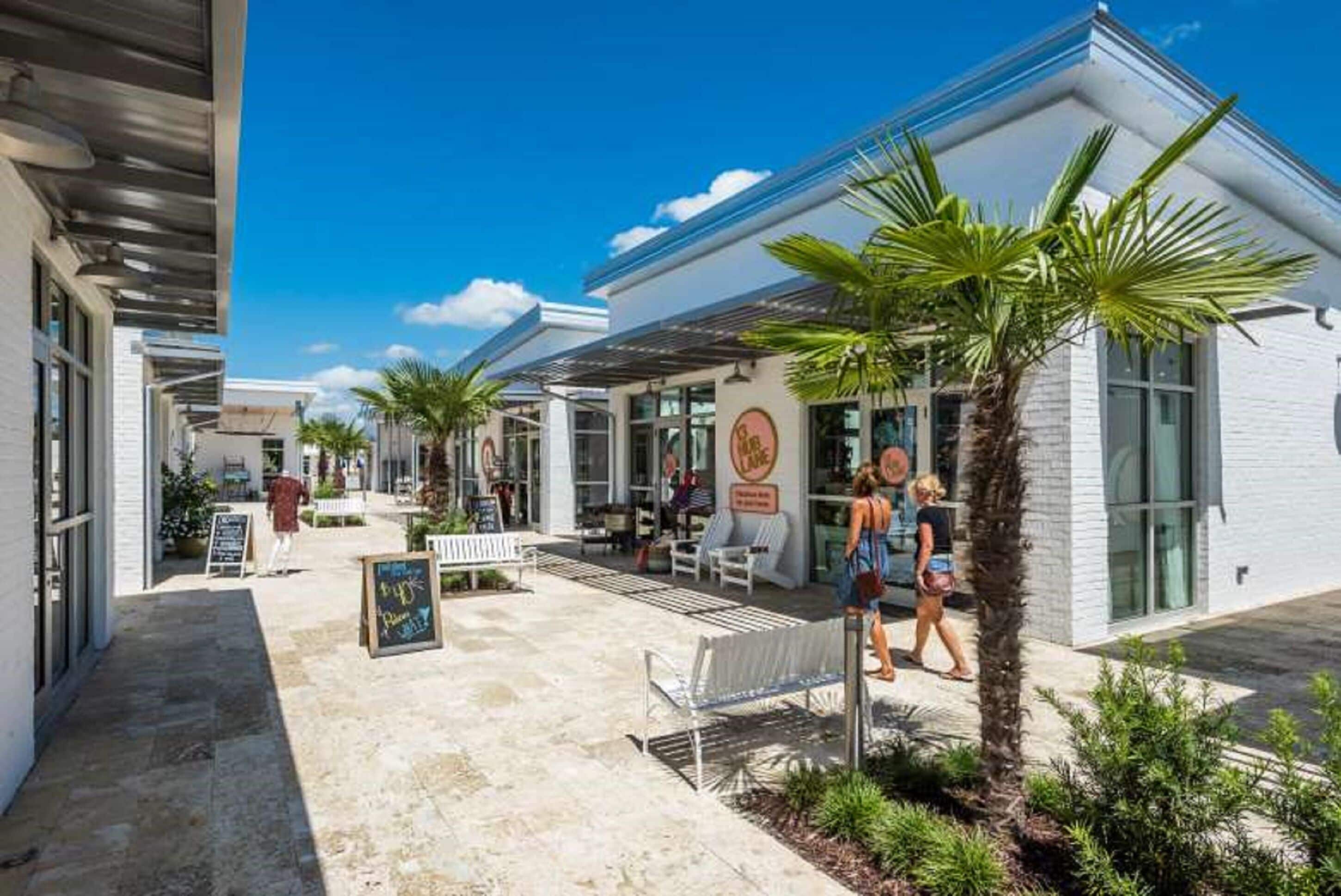 Un edificio moderno con un patio, asientos al aire libre y palmeras.