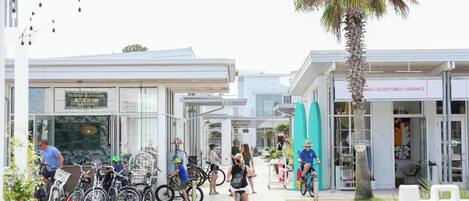 Un edificio moderno con escaparates de vidrio, zona de estacionamiento para bicicletas y una palmera.